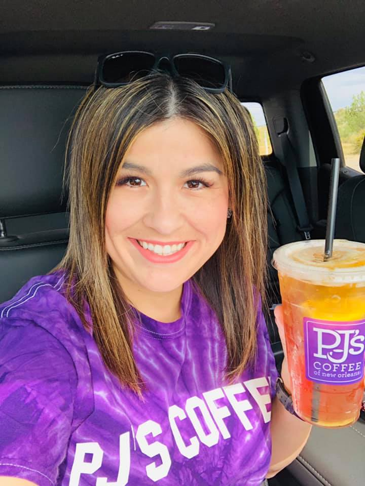 Marielena smiling, holding a PJ's Coffee iced tea and wearing a PJ's Coffee t-shirt. 